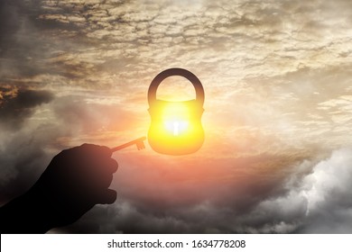 Silhouette of a hand with a key opening a padlock into a heavenly sphere for the spiritual concept of key to tranquility. 