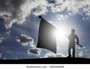 Silhouette of a man waving a big flag on top of a hill against a surreal sunny day for the concept of successfully capturing the hill. 