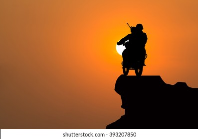 Silhouette Of Military Motorcycle On A Cliff With Sunset.