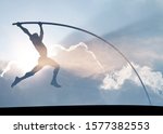 Silhouette of a pole vaulter vaulting across a surreal azure sky for the concept of hardwork propelling to success.