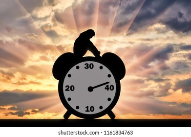 Silhouette Of A Sad Woman Sitting On A Clock Where The Arrow Shows Almost 40 Years Old. Conceptual Image Of Impending Menopause In Women