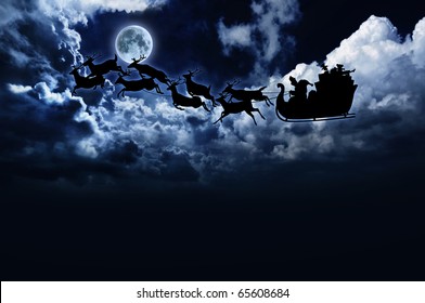 Silhouette Of Santa Sleigh And Reindeer In Night Sky With Full Moon