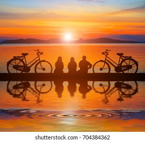 silhouette vintage  bike and group friend  in  the holiday and water reflection on sunrise time - Powered by Shutterstock