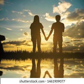 silhouette young man standing hand in hand with love on sunset and sky background