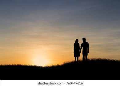 Silhouettes of couple man and woman in nature sunset background. Vintage filter. Love concept.