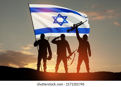Silhouettes of soldiers with Israel flag against the sunrise in the desert. Concept - armed forces of Israel.
