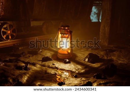 A singular old-fashioned lantern casts a warm, golden glow in the enveloping darkness, highlighting the intriguing depths of a historic mine.