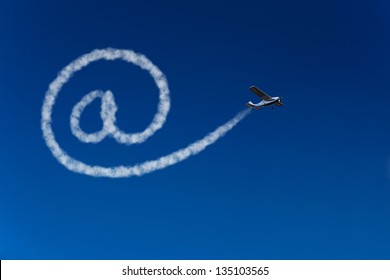 Skywriting airplane painting an at sign in the blue sky
