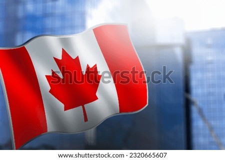 A small flag of Canada on the background of a blurred city background