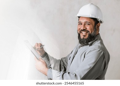 Smiling male construction worker, engineer, with hard hat and holding a clipboard. Male engineer, construction worker in a hard hat, working on white plain background with copy space. - Powered by Shutterstock