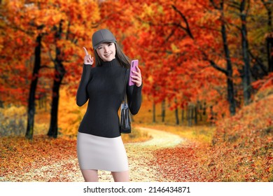 A smiling woman in a hat poses with a pink smartphone in hand as she strolls through a forest of bright red leaves.3D illustration 3D rendering