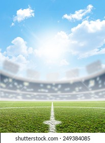 A Soccer Stadium With A Marked Green Grass Pitch In The Daytime Under A Blue Sky