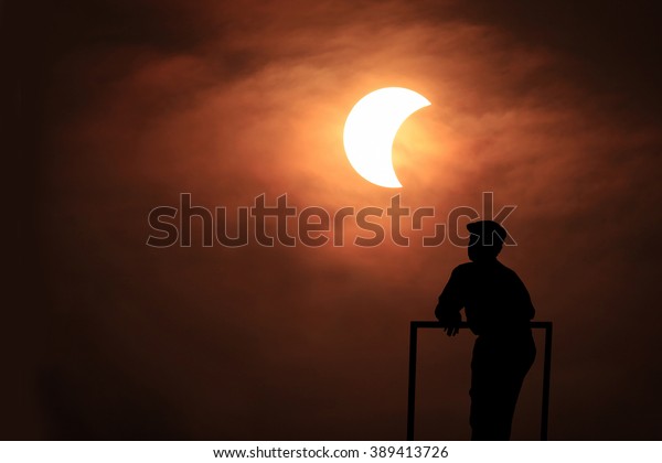 Solar eclipse with clouds and silhouettes\
foreground image.