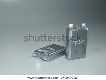 A solid-state battery. They are placed side by side on a light grey background