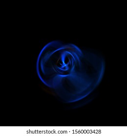 Spinning rays of light isolated on black background. Graphic 2D illustration of glowing colorful light particles in circular motion.