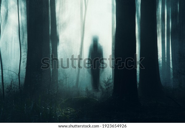 A spooky concept of a ghostly figure\
silhouetted between trees in a forest on a moody, foggy winters\
day. With a grunge, abstract edit. England,\
UK