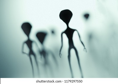 Spooky silhouettes of aliens and bright light in background. 3D rendered illustration.