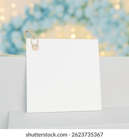Square white gift tag mockup with golden cord. Square favor tag mockup with copy space. Green balloons and blurred background lights. 3D rendering.