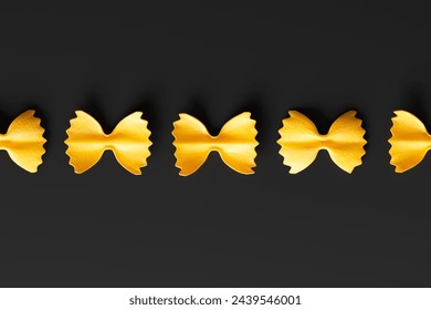 Striking image of vibrant yellow bow tie pasta meticulously arranged in a row against a stark black background, showcasing its unique shape and inviting texture. - Powered by Shutterstock