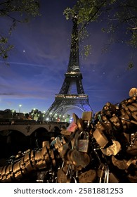 A stunning nighttime view of the Eiffel Tower, illuminated against a dark sky with clouds. The warm and cool lighting highlights the intricate iron structure, creating a captivating cityscape shot.