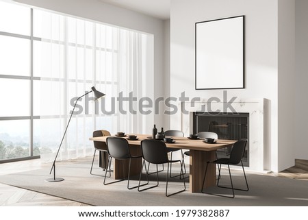 Stylish designed modern interior of dining room with fire pace, table and six black chairs. Minimalist style of home decor. Empty white framed poster on wall. 3d rendering
