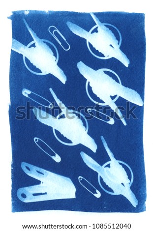 sun-printing or cyanotype process. Some items and objects like scissors, pins, clothes peg, saw, staple, clamp lying on a watercolour paper covered with a special photosensitive liquid. 