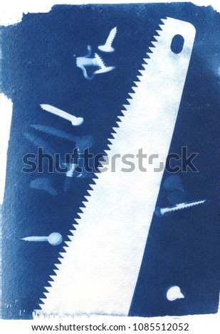 sun-printing or cyanotype process. Some items and objects like scissors, pins, clothes peg, saw, staple, clamp lying on a watercolour paper covered with a special photosensitive liquid. 