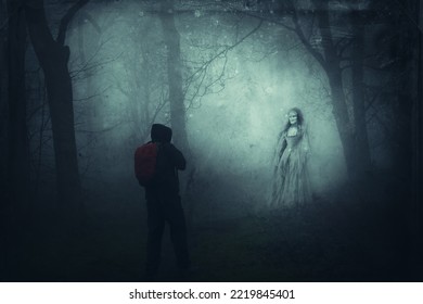 A supernatural concept. A hiker looking at a demonic, woman, ghost, wearing a vintage dress. Standing in a spooky foggy forest. On a creepy winters day