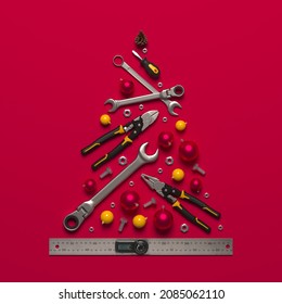 A symbolic Christmas tree made of construction tools on a red background. Creative template of a New Year greeting for building and engineering companies. 3D render.