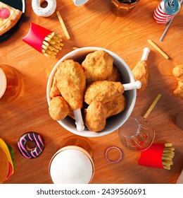 A tantalizing overhead shot featuring a wide variety of fast food options, from savory burgers to sweet donuts, laid out on a wooden table, embodying the indulgence in quick meals. - Powered by Shutterstock