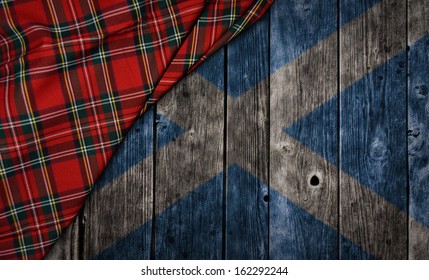 tartan textile on wooden background with scotland flag