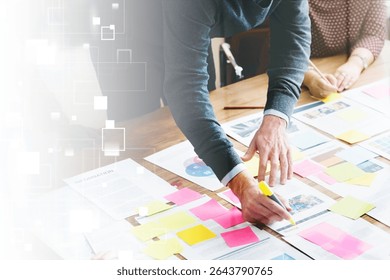 Teamwork, collaboration, and brainstorming with diverse hands arranging colorful sticky notes and documents on a table. Creative planning and teamwork in action. Business strategy and development.