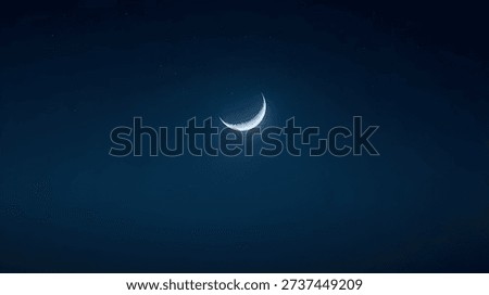 Thin crescent moon in deep blue night sky.