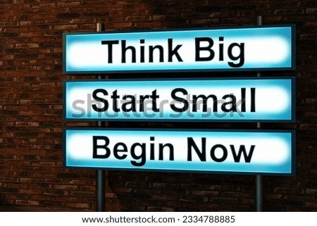 Think Big, start small, begin now. Black letters on a blue illumintaed light box, red brick wall. Thinking, ideas, beinnings. small business, strategy, motivation, encouragement. 3D illustration