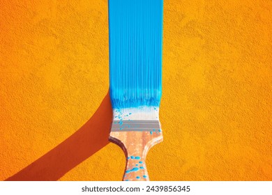 This compelling image captures a vibrant blue paint streak across a textured orange wall, showcasing a daring contrast of colors and the beauty in simplicity and creativity.