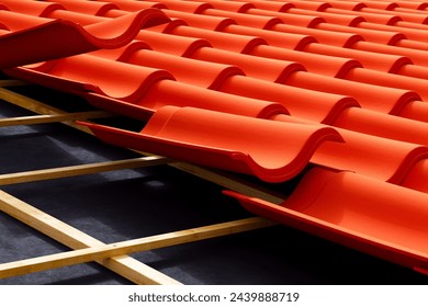 This image captures the stark, vibrant contrast of bold red roof tiles neatly aligned atop a wooden structure, offering a glimpse into precise roofing craftsmanship.