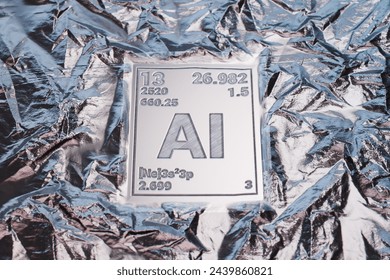 This image features the element symbol for aluminum, AI, along with its atomic number 13 and mass 26.982, against a reflective, silver metallic foil backdrop.