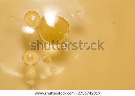 This image features floating bubbles and oil drops in a light yellow liquid, showcasing an abstract and smooth texture perfect for various design projects.