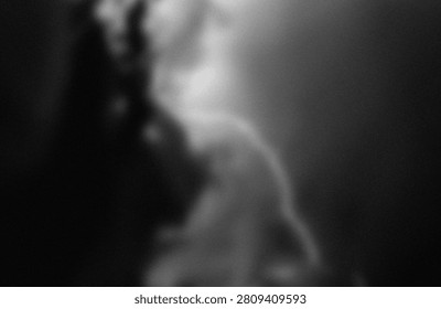 This image features a highly blurred and indistinct silhouette of a person, likely captured in low light or with a shallow depth of field. The figure appears to be standing or moving against a dark background, with minimal detail visible, emphasizing the form and shape rather than specific features or context. The overall ambiance suggests a moody or atmospheric setting, possibly indicating artistic intent or a candid snapshot in a dim environment.