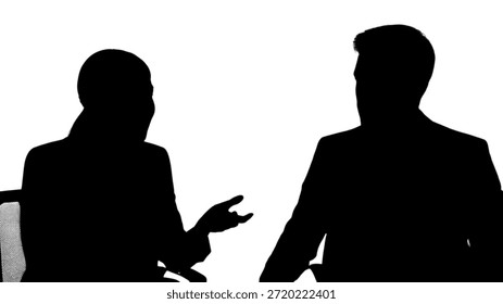 This powerful silhouette image captures two professionals engaged in an intense and dynamic conversation or interview session. The figures, rendered in stark black against a pure white background, face each other, with one person on the left gesturing with their hand, indicating active participation or explanation. The clear contrast emphasizes the interaction and the subjects' forms without revealing specific identities, making it versatile for various conceptual uses related to communication, discussion, or business meetings. The setup suggests a serious and focused exchange of ideas.