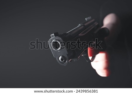 This striking image captures a tense moment as a hand tightly holds a loaded pistol, aimed directly forwards, set against a dark, ominous background. It evokes themes of danger, defense, and urgency.