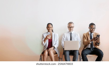 Three diverse people sitting, using devices. Diverse group with laptops and phones. Diverse professional in. technology and communication focus. Tech, business concept with copy space. - Powered by Shutterstock