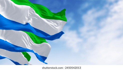 Three Sierra Leone national flags waving in the wind on a clear day. Tricolor with horizontal stripes in green, white and blue. 3D illustration render. Selective focus. Close-up - Powered by Shutterstock