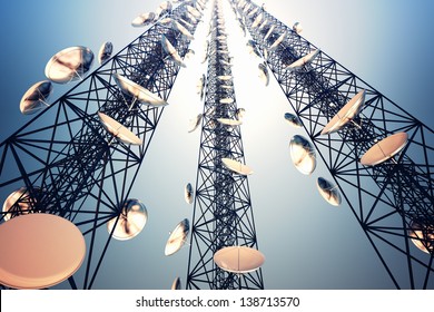 Three tall telecommunication towers with antennas on blue sky. View from the bottom.