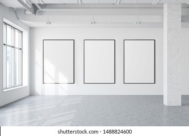 Three vertical mock up poster frames hanging in modern industrial style gallery with white walls, concrete floor, windows with cityscape and pipes. Concept of advertising and art. 3d rendering