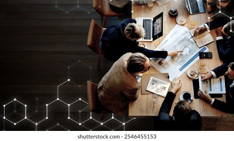 Top view of diverse business people meeting at a table with laptops, documents, and coffee, discussing business plans and ideas in a modern office setting. Diverse business meeting concept. - Powered by Shutterstock