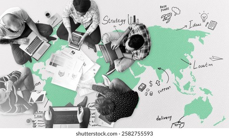 Top view of diverse group working on laptops over a world map. Collaborative strategy planning with documents. Teamwork in a global context. Startup business team working together on the floor.