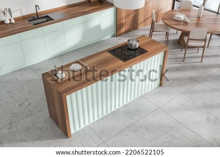Top view of green kitchen interior with bar island, eating zone with table and chairs on grey tile floor. Panoramic window and stylish decoration. 3D rendering