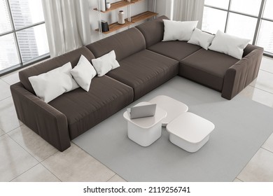 Top View Of Living Room Interior With Brown Sofa And Armchair, Coffee Table With Laptop On Carpet, Beige Tiled Floor, Window On City View. Minimalist Relaxing Space With Decoration, 3D Rendering