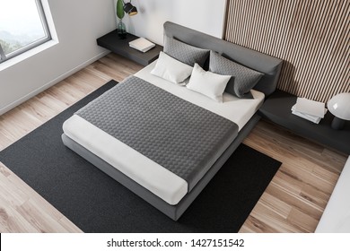 Top View Of Minimalistic Bedroom With White And Wooden Walls, Wooden Floor, Gray Master Bed With Black Bedside Table And Gray Carpet. 3d Rendering